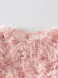 Détail du col d'une robe rose pour fille avec sequins brillants et textures à franges