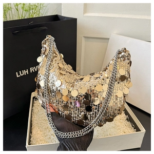 Detailed close-up of golden sequin crescent bag with silver chain and luxury packaging