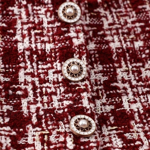 Detalle del vestido de tweed rojo y blanco con hilos dorados y botones de esmalte y perlas