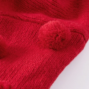 Detail of red cable-knit fabric featuring a matching soft fuzzy pom-pom texture
