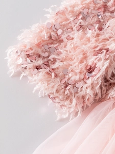 Détail d'une robe de fille avec sequins roses et finitions délicates en plumes douces