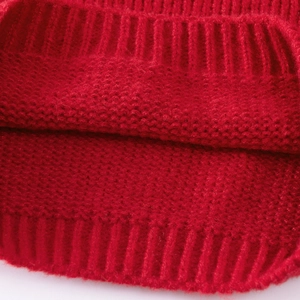Macro detail of red knit sweater fabric showing ribbed texture and soft wool fibers