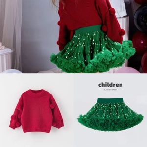 Detail of red knit sweater with 3D pompoms and green tutu skirt with gold stars