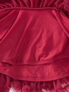 Close-up of dark red knit fabric with multi-layered mesh ruffles and detailed stitching