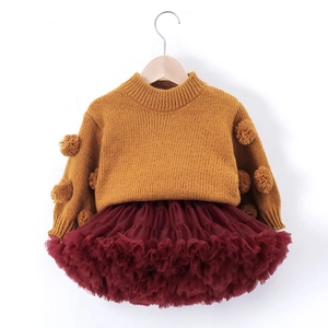 Detailed view of the yellow knit sweater with 3D pom-poms and layered red tutu skirt