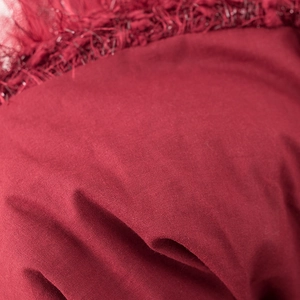 Detalle de la tela del vestido rojo festivo con textura suave y bordes de flecos finos