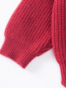 Detail of red ribbed knit sweater featuring shiny silver metallic yarn and ribbed cuffs
