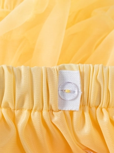 Detail of yellow tulle tutu skirt showing elastic waistband and clear button closure