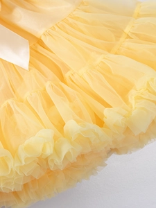 Detail of multi-layered light yellow tulle tutu skirt with ivory satin ribbon tie