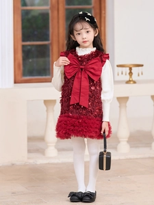 Detalle de vestido festivo rojo con lentejuelas para niña y suéter de punto color crema