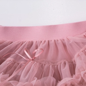 Detail of pink tutu skirt featuring elastic waist, layered mesh, and satin bow