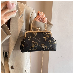 Détail du sac à main noir avec broderie papillon dorée et fermoir en métal doré