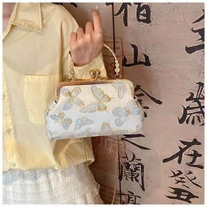 Détail de la broderie papillon sur un sac en soie vintage avec poignée en métal dorée