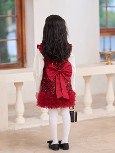 Detalle del vestido de terciopelo rojo para niña con lazo grande y mangas de punto