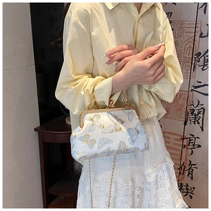 Detail of silk vintage crossbody bag with butterfly embroidery and golden metal handle