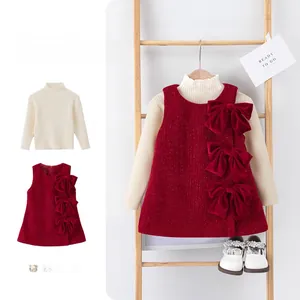 Detalle de vestido de terciopelo rojo con lazos y jersey de punto marfil para niña