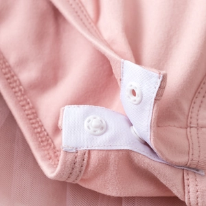 Detailed close-up of soft pink cotton fabric with white resin snap buttons on a romper