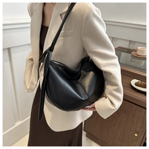 Detail of black leather saddle bag showing adjustable knotted strap and silver metal zipper