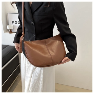 Detail of dark brown leather saddle bag with vertical stitching and adjustable strap