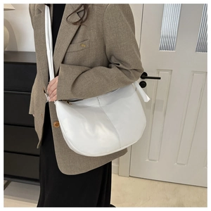 Minimalist white PU leather crescent bag shown with a widened shoulder strap on a model