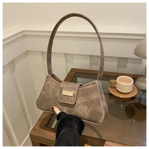 Detail view of retro brown shoulder bag with gold metal buckle on a cozy wooden table