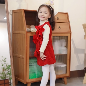 Detalle del vestido de terciopelo rojo para niña con lazos y jersey blanco de cuello alto