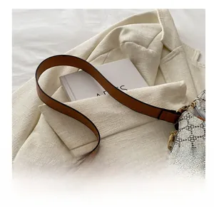 Détail de la bandoulière en cuir marron et du motif floral géométrique du sac à main