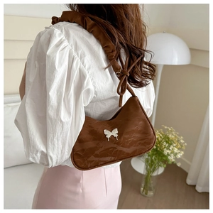 Detail view of brown crescent shoulder bag with white butterfly motif and ruched strap