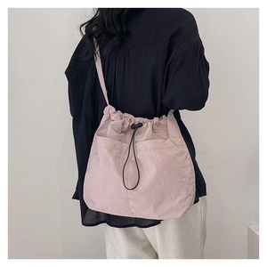 Detail of pink drawstring crossbody bag showing fabric texture and adjustable strap