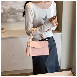 Close-up of pink patent leather handbag with knot handle and golden hardware detail
