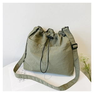 Detail of sage green nylon bucket bag featuring a drawstring closure and wrinkled texture
