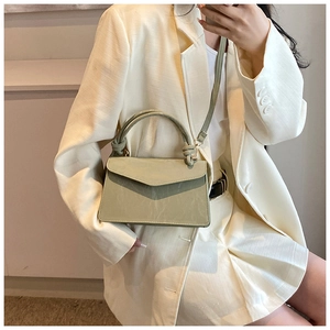 Detail of light green crossbody bag featuring a knotted handle and matte faux leather texture