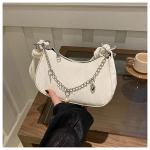 Détail du sac blanc à texture marbrée avec chaîne argentée, perle et breloque coeur