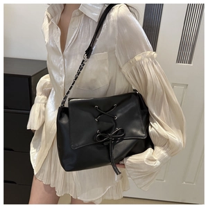 Detail of black PU leather tote with cross-lace design and metal chain strap