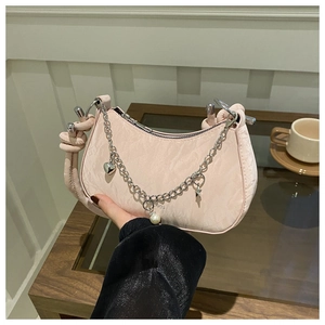 Détail du sac selle rose clair avec breloques cœur et bandoulière torsadée