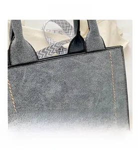 Detail van grijze tote bag met gouden FASHION BAG print en contraststiksels