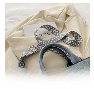 Detail van blauwe handtas met geometrische stoffen riem op een beige blazer