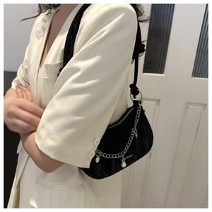Détail du sac de selle noir avec chaîne argentée, perle et pendentif étoile élégant