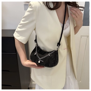 Détail du sac demi-lune noir en tissu texturé avec chaîne argentée et breloque perle