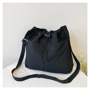 Close-up of black nylon drawstring crossbody bag with adjustable strap and side pocket