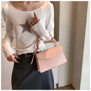 Detail of pink pebbled leather small square bag with knot handle and gold hardware