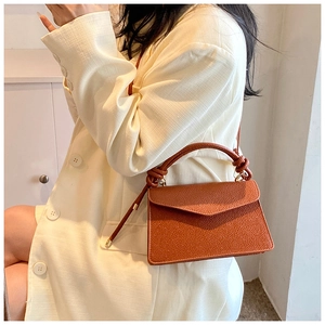 Brown textured small square bag shown as a crossbody on model in white blazer
