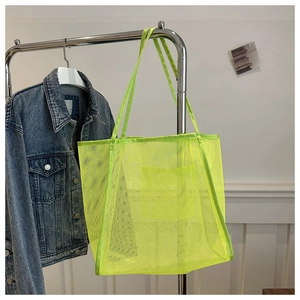 Detail of neon green mesh tote bag with large capacity hanging on a silver hanger