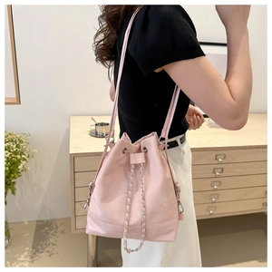 Seitenansicht einer rosa Leder-Eimertasche mit Kettendetail und Kordelzugverschluss