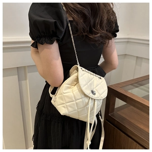 Detail of cream quilted mini backpack with silver chain strap and drawstring closure