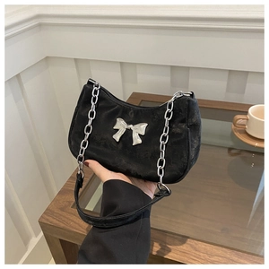 Detailed close-up of black fabric hobo bag featuring silver metal bow and chain strap