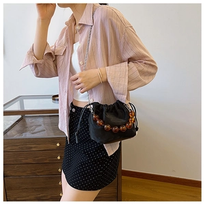Détail du sac seau noir avec perles en résine ambre et bandoulière chaîne argentée