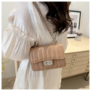 Détail du sac matelassé camel avec bandoulière chaîne argentée et boucle diamants