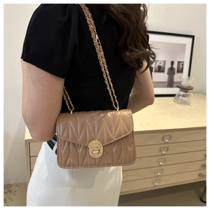 Detail of light brown quilted crossbody bag with gold chain strap in an elegant setting