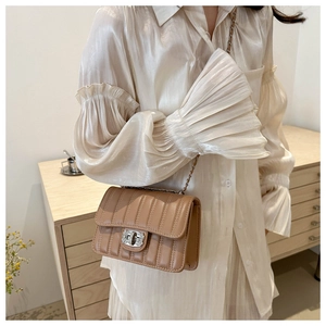 Vue détaillée du sac matelassé marron avec boucle en strass étincelants et bandoulière chaîne
